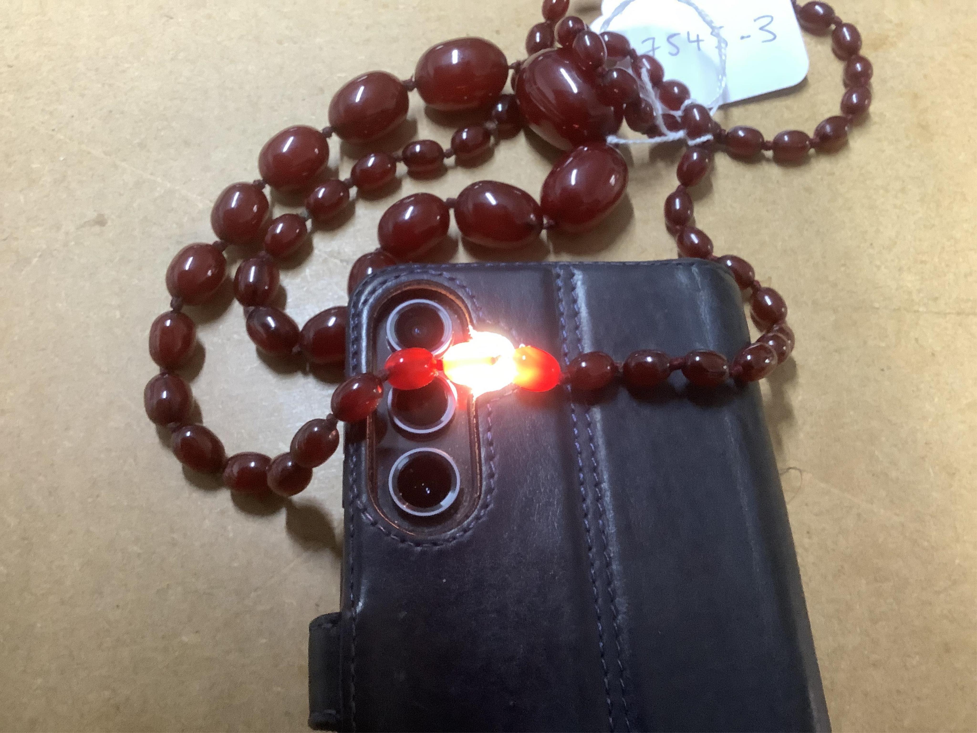 A single strand graduated oval simulated cherry amber bead necklace, 94cm, gross 63 grams. Condition - fair